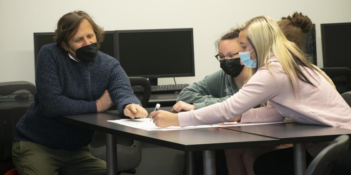 Professor assisting students in classroom.